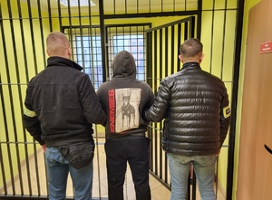 dwóch policjantów stoi z zatrzymanym przed celą.