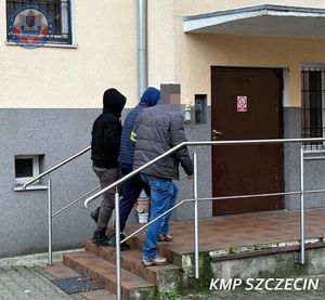 Dwaj policjanci prowadzą zatrzymanego.