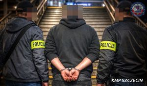 dwóch policjantów stoi obok zatrzymanego.