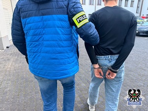 policjant prowadzi zatrzymanego.