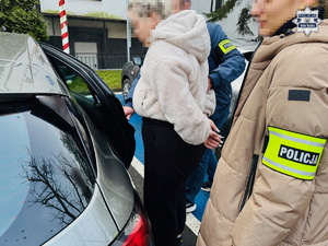 policjanci prowadzą zatrzymaną.