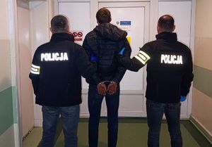 policjanci stoją z zatrzymanym.