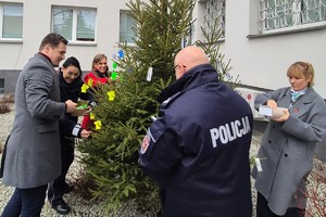 Policjanci oraz inne osoby podczas ubierania odblakowej choinki.
