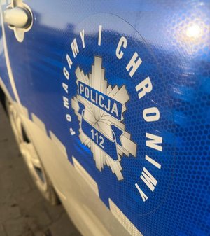 Logo "Pomagamy i chronimy" na drzwiach radiowozu.