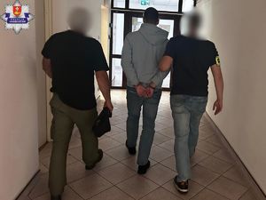 Dwaj funkcjonariusze prowada korytarzem zatrzymanego.