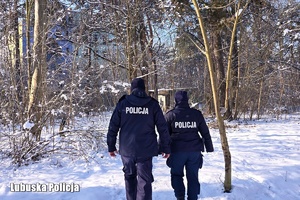 policjanci zimą patrolują las.