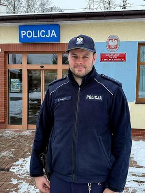 Dzielnicowy z Łochowa stoi na tle posterunku