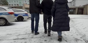 Ubrani po cywilnemu policjanci prowadzą zatrzymanego.