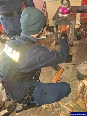 Policjant rozpala ogień w piecu.