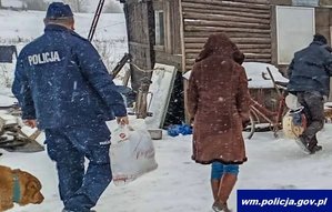 zima, podwórko, na pierwszym planie widać policjanta obok którego idzie pies. Przed nimi idzie kobieta. Przed nią idzie senior.