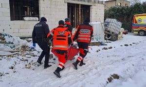 Policja i ratownicy medyczni pomagają bezdomnemu. Mężczyzna zawinięty w koc termiczny