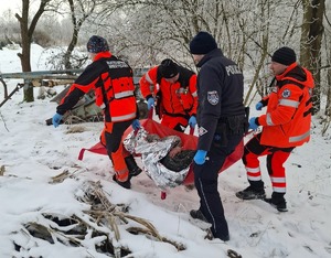 policjanci i ratownicy na tle pustostanu. Niosą zawiniętego w koc termiczny mężczyznę