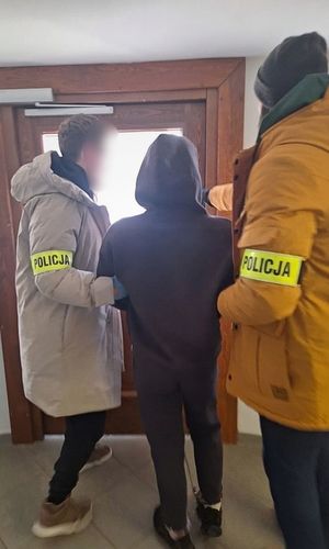 Policjanci prowadzą zatrzymanego mężczyznę.