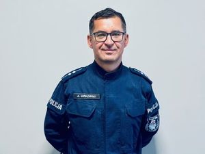 Umundurowany dzielnicowy pozuje do zdjęcia.