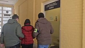 Dwaj policjanci prowadzą zatrzymanego.