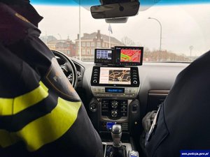 Policyjny radiowóz od środka i widoczne rękawy polskiego i holenderskiego policjanta.