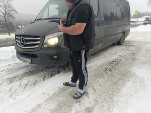 policjant sprawdza bus. Kierowca stoi przy samochodzie.