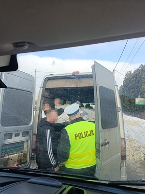 policjant sprawdza bus. Kierowca stoi przy samochodzie.