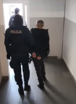 Dwaj policjanci prowadza zatrzymanego.