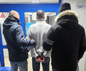 Dwaj policjanci prowadzą zatrzymanego.