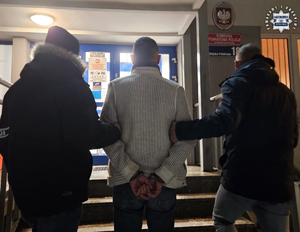 Dwaj policjanci prowadzą zatrzymanego.
