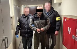 dwóch policjantów prowadzi zatrzymanego.