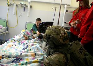 Funkcjonariusze BOA przy szpitalnym łóżku, w którym leży mały chłopczyk..