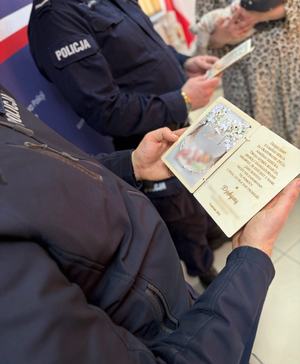 policjanci stoją na tle napisu Komenda Wojewódzka Policji w Augustowie.
