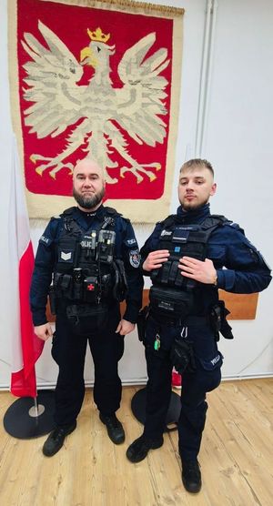 Dwaj umundurowani policjanci pozują do zdjęcia.
