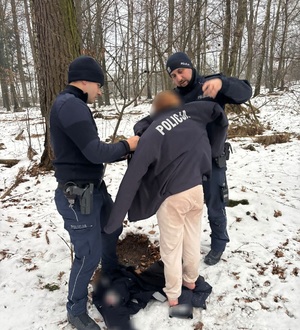 policjant daje kurtkę dziewczynce. obok stoi drugi policjant.