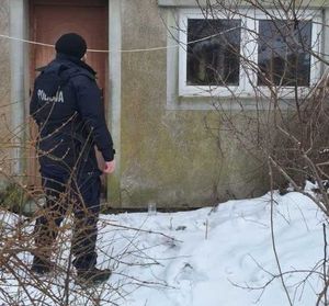 Policjant przed opuszczonym budynkiem.