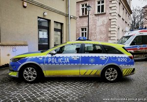Policyjny radiowóz zaparkowany przed budynkiem.