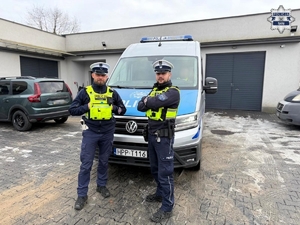 Policjanci stoją przy radiowozie.