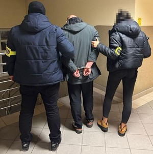dwóch policjantów prowadzi zatrzymanego.