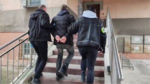 Policjanci prowadzą mężczyznę w kajdankach.