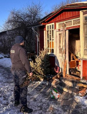 Policjant stoi przed wejściem do posesji.