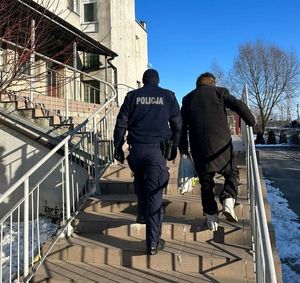 Policjant idzie po schodach z mężczyzną.