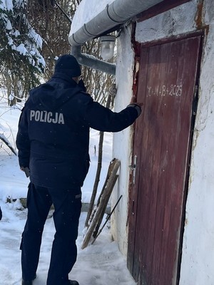 Policjant stoi przy drzwiach wejściowych do domu.