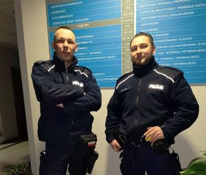 Dwaj umundurowani policjanci pozują do zdjęcia.