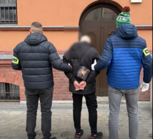 Policjanci prowadzą zatrzymanego.