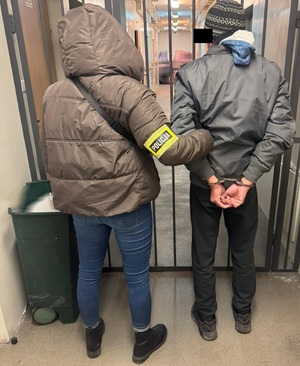 Zatrzymany prowadzony przez policjantkę.