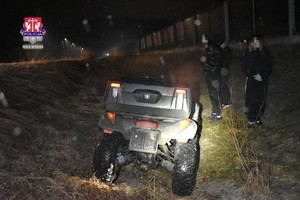 noc. w rowie stoi quad. obok stoi dwóch mężczyzn.