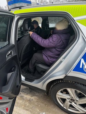 Starsza kobieta siedzi w radiowozie policyjnym.