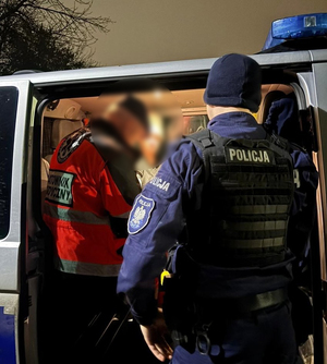 Ratownik i Policjant stoją przy karetce pogotowia.