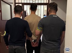 Dwóch nieumundurowanych policjantów prowadzi zatrzymanego.