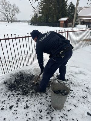policjant napełnia wiadro węglem.