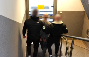 Dwaj nieumundurowani policjanci prowadzą zatrzymanego.