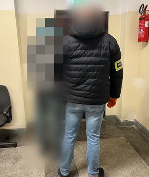 policjant stoi z zatrzymanym.