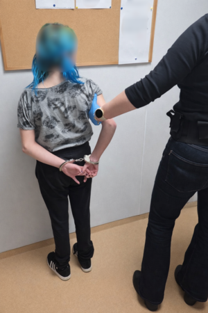 Zatrzymana trzymana przez funkcjonariusza.