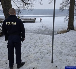 Policjant na brzegu, mężczyzna na zamarzniętej tafli lodu.